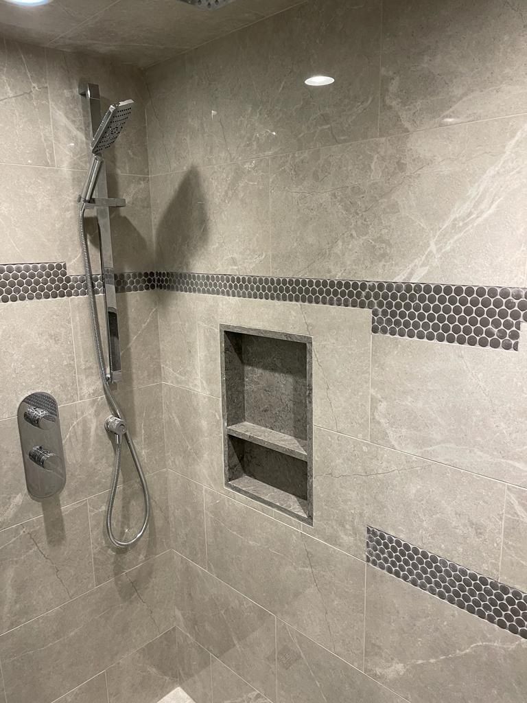 Grey marble shower with penny-round accent stripe and niche