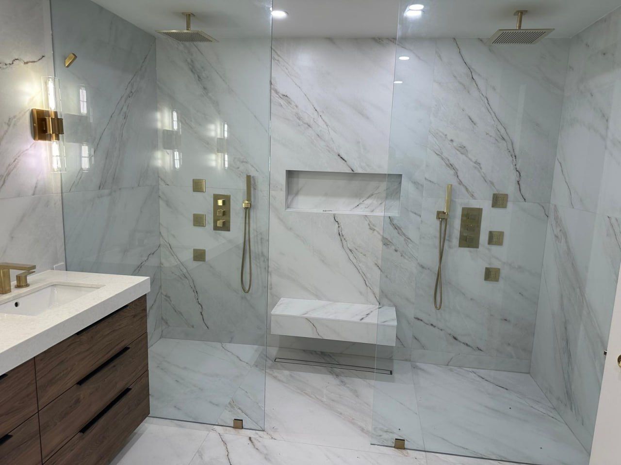 Large double marble walk-in shower with brushed gold body jets