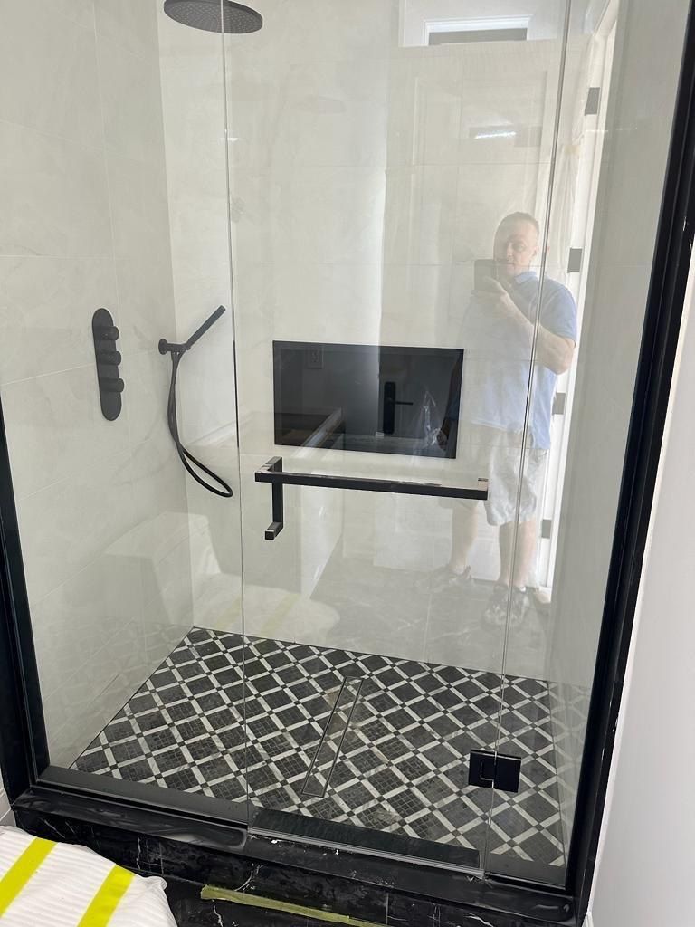 Light-tile shower with black fixtures and checkerboard mosaic floor