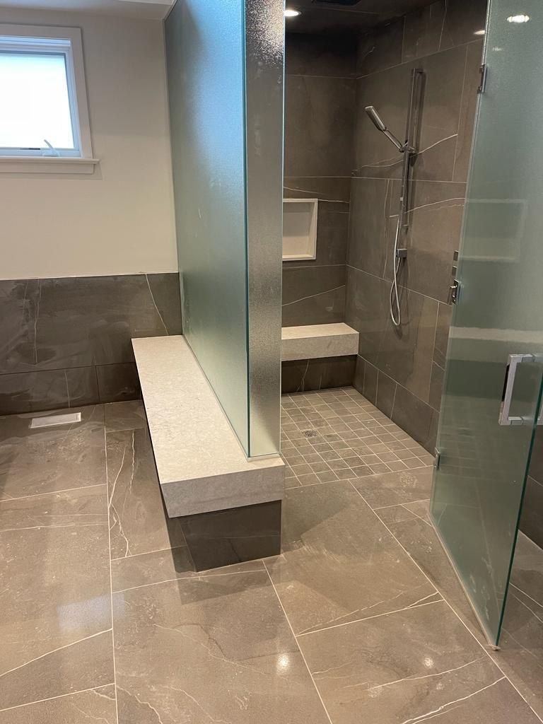 Grey stone double shower with twin benches and glass partition
