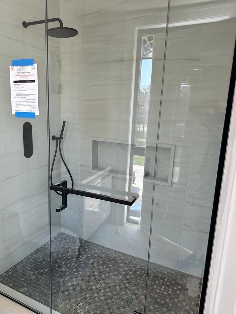 White marble shower with black fixtures and mosaic floor