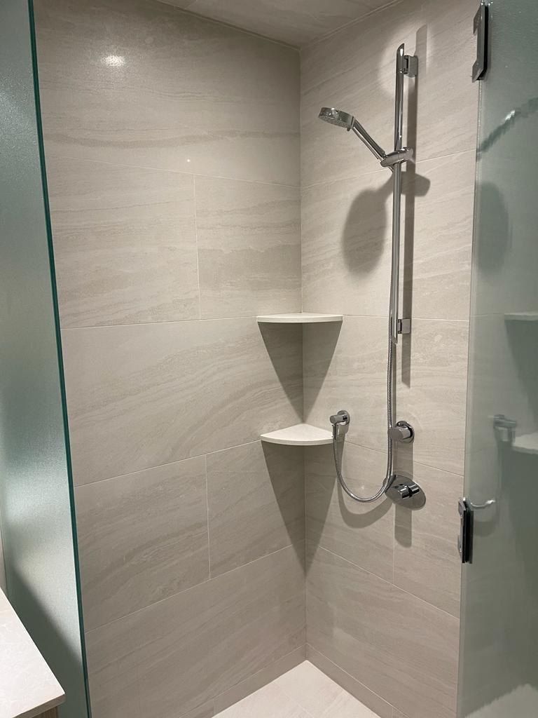 Travertine-look shower with corner shelves and chrome fixtures