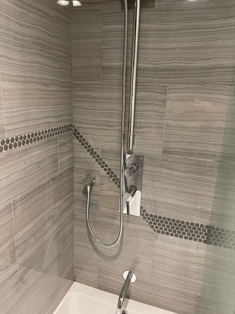Grey wood-look tile tub surround with penny-round accent
