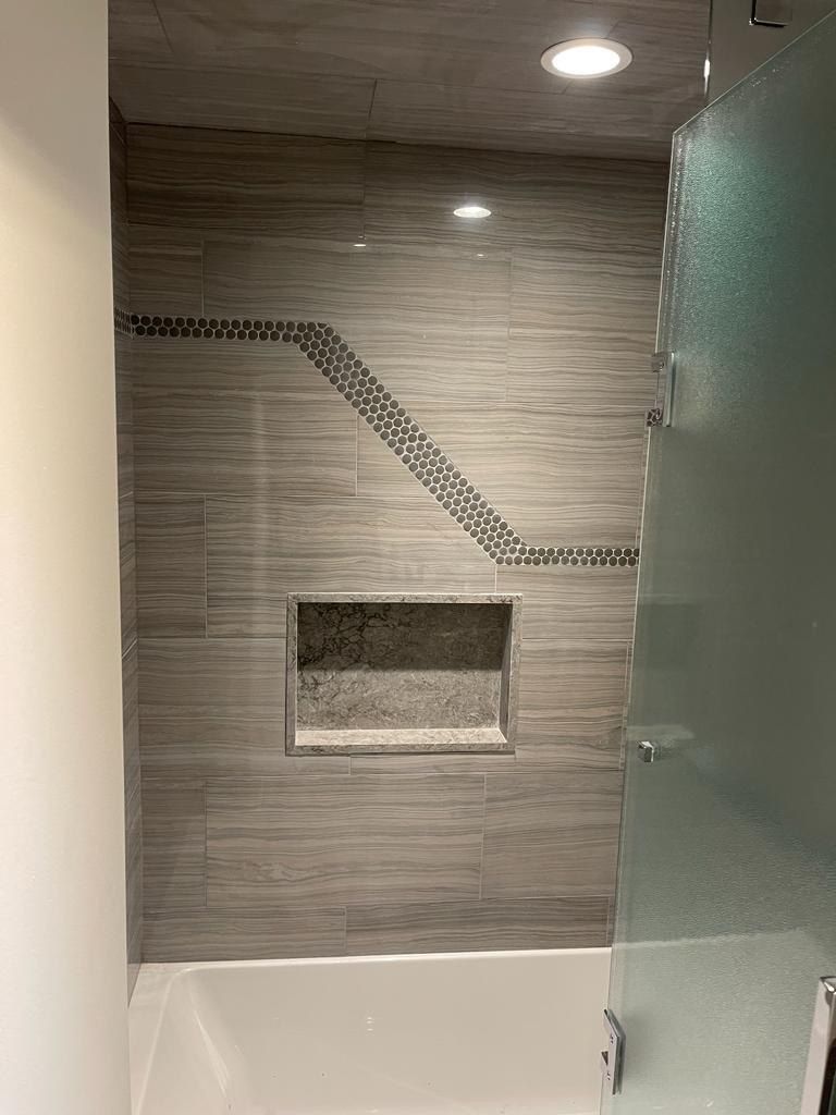 Grey wood-look tub and shower with penny accent and niche