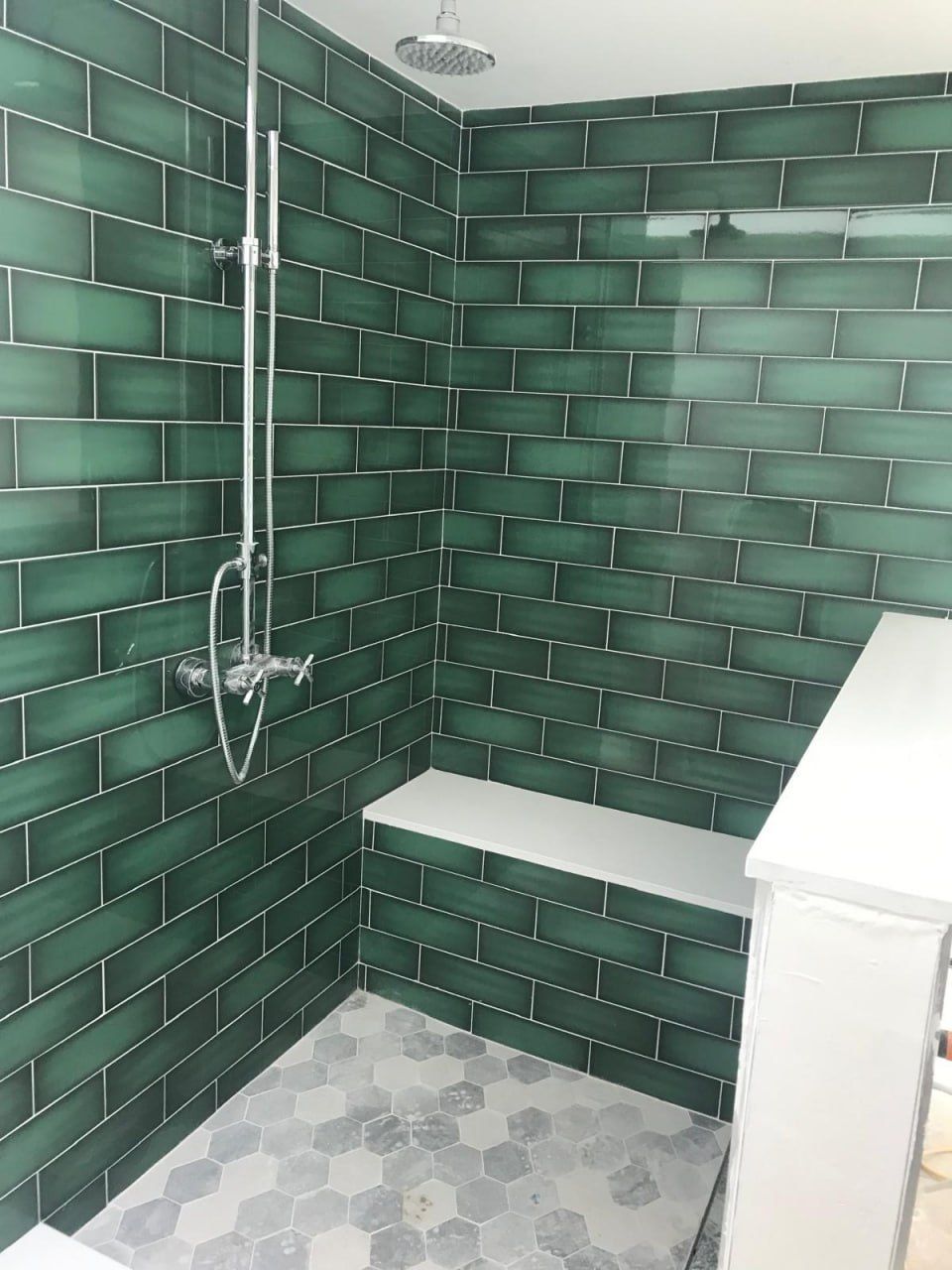 Emerald green subway-tile shower with bench and hex floor