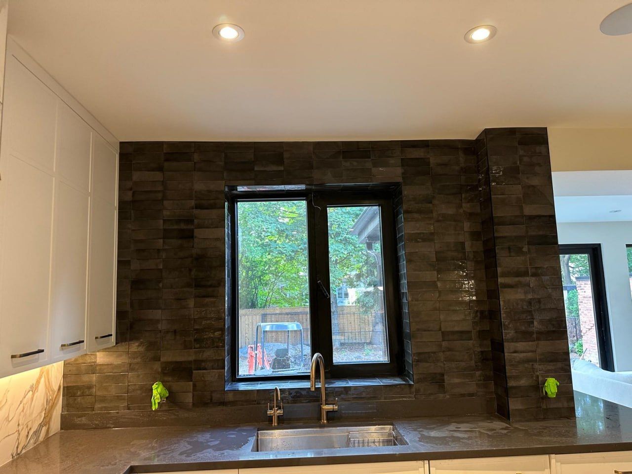 Dark glossy zellige-look backsplash around a kitchen window