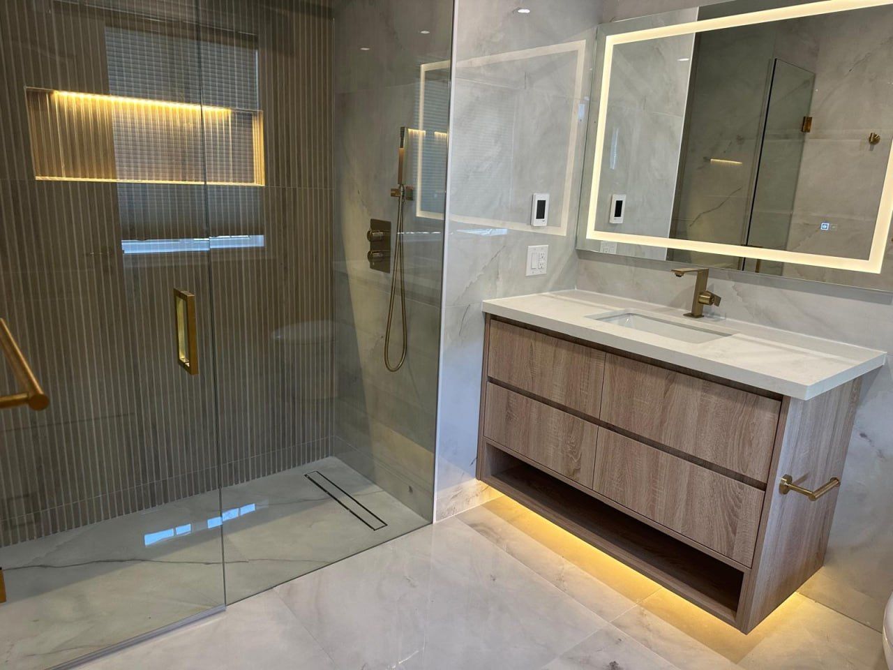 Fluted-tile shower with floating wood vanity and backlit mirror