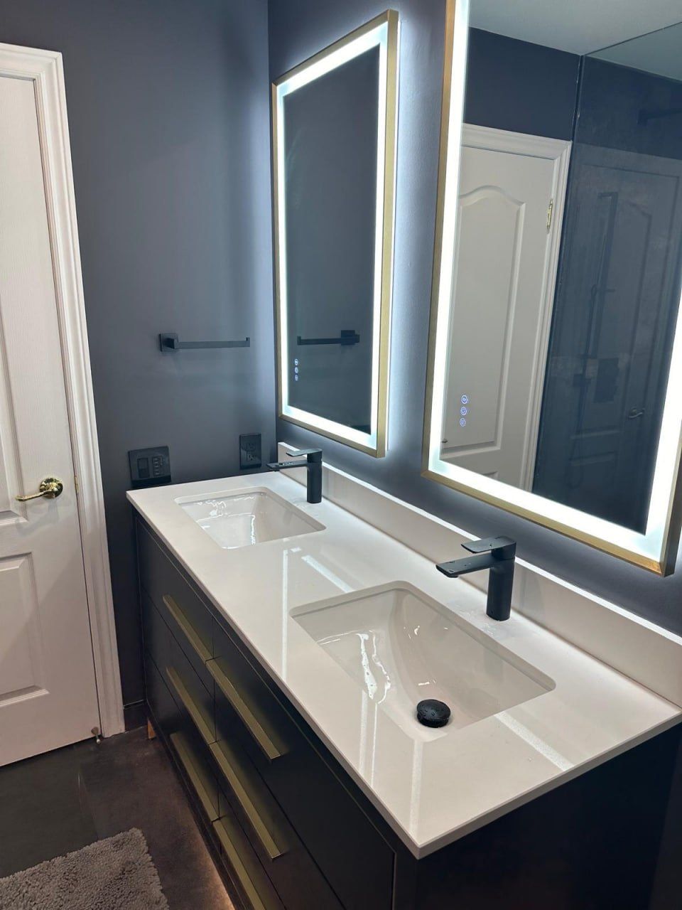Dark ensuite with black vanity, black fixtures and LED mirrors