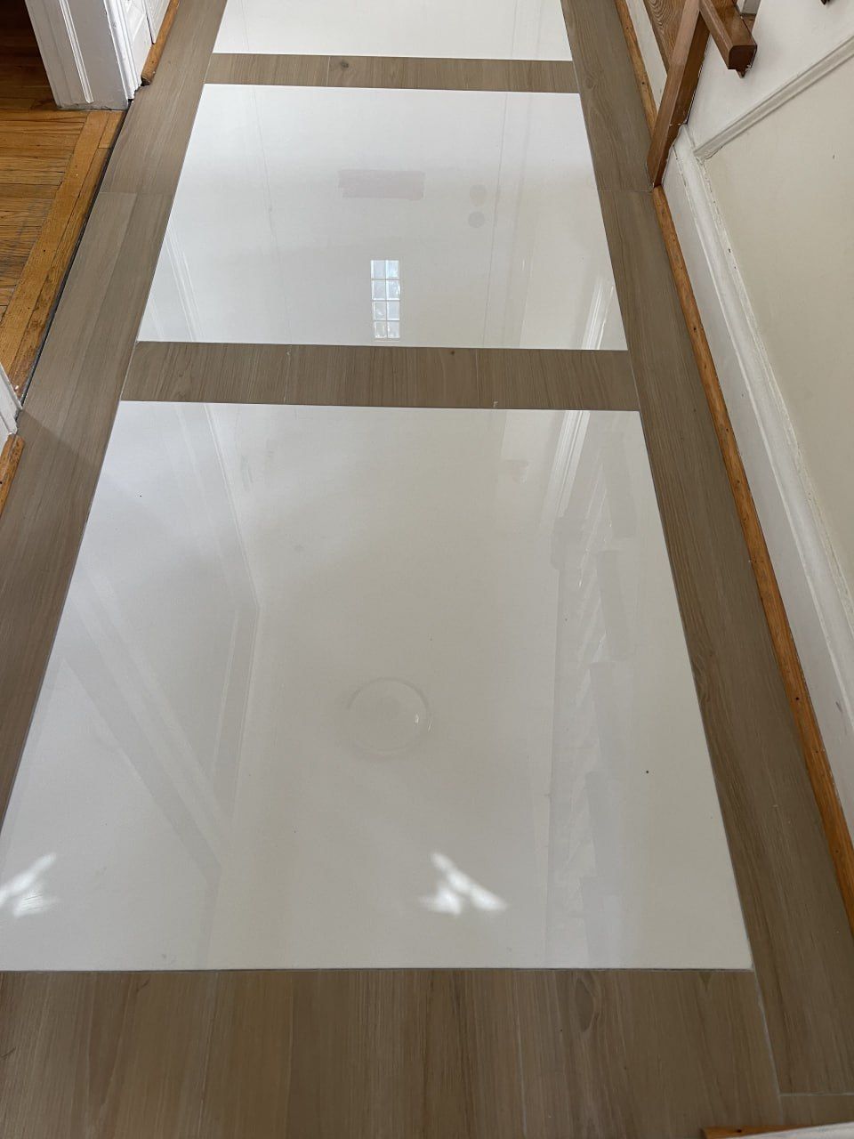 Gloss floor tile with wood-look border inlay in a hallway