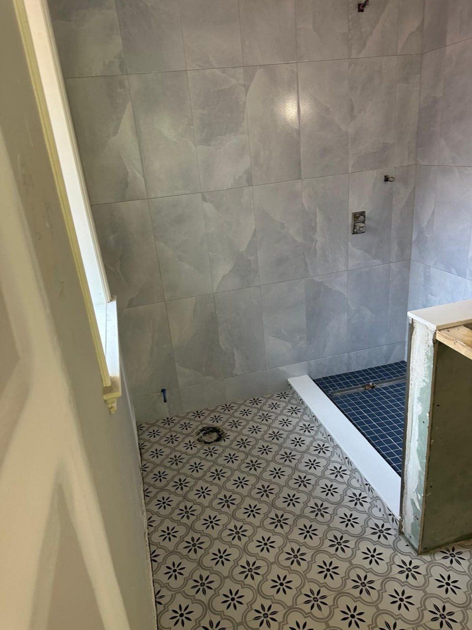 Shower with mosaic pan and patterned floor mid-installation