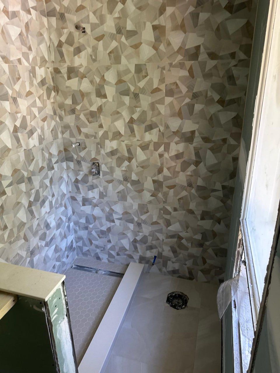 Geometric mosaic shower wall with hex pan in progress