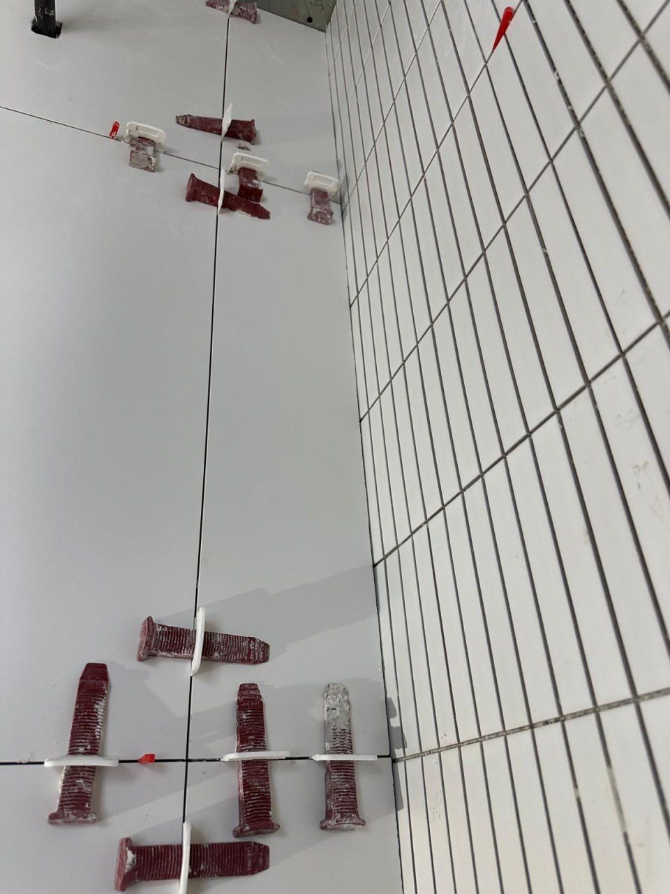 Wall tiles held flat with levelling system
