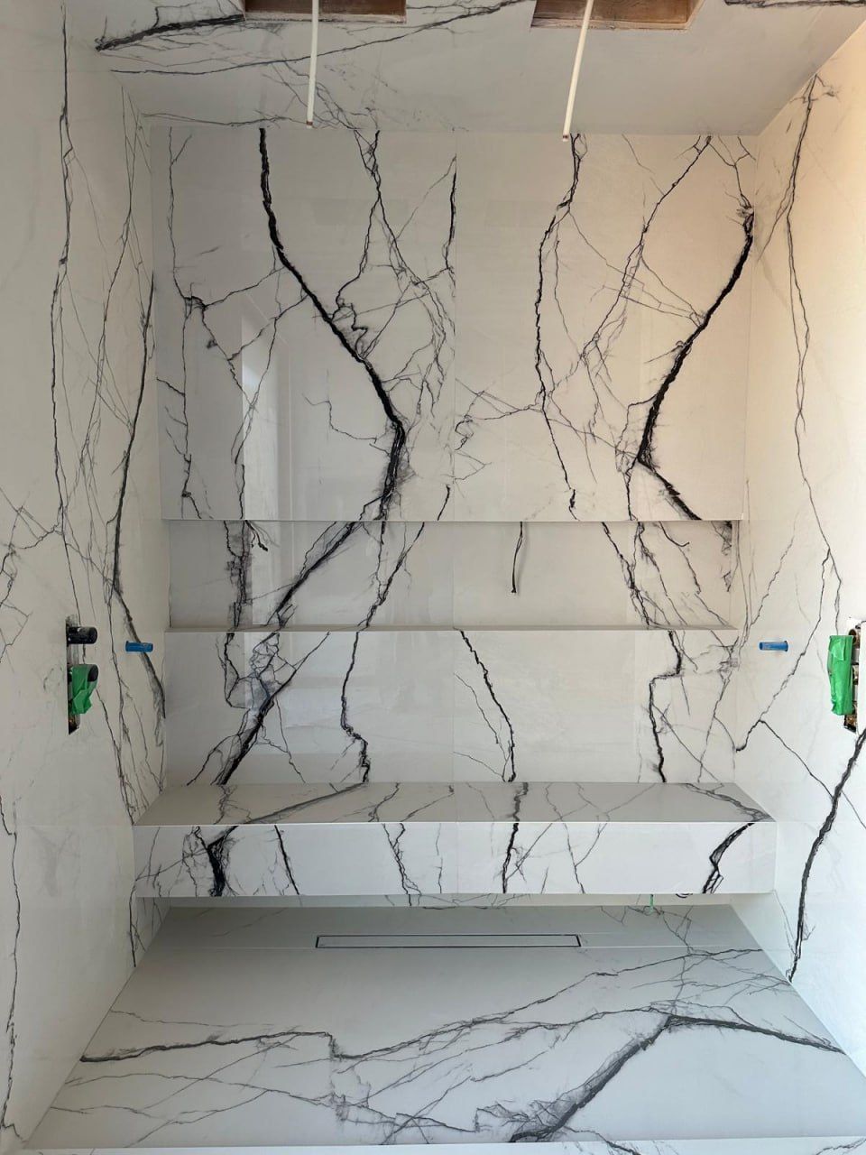 Book-matched marble shower with built-in bench under construction