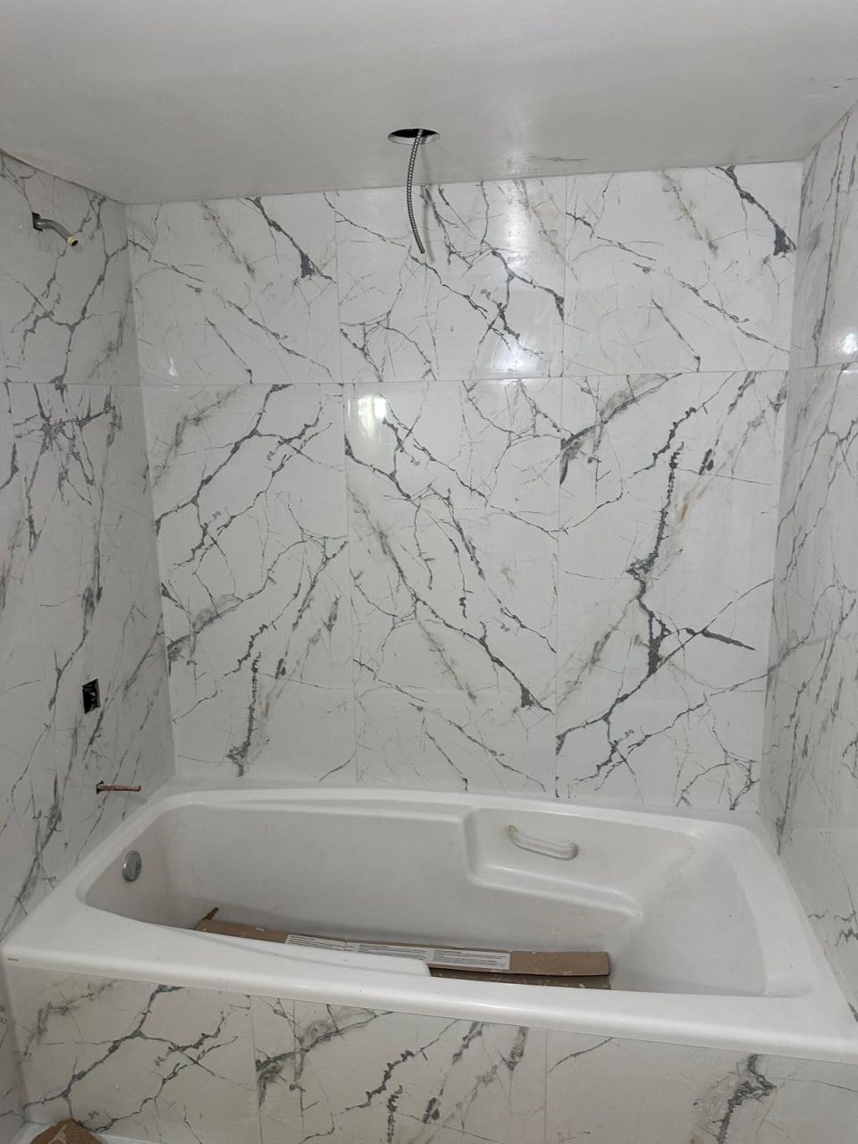 Marble-look tub surround tiled to ceiling
