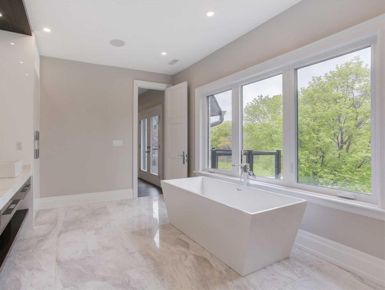 Marble-floor bathroom with freestanding tub and garden view