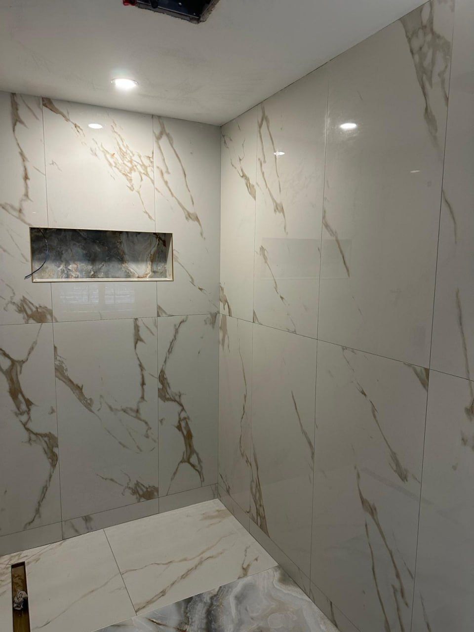 Calacatta marble shower with onyx feature niche