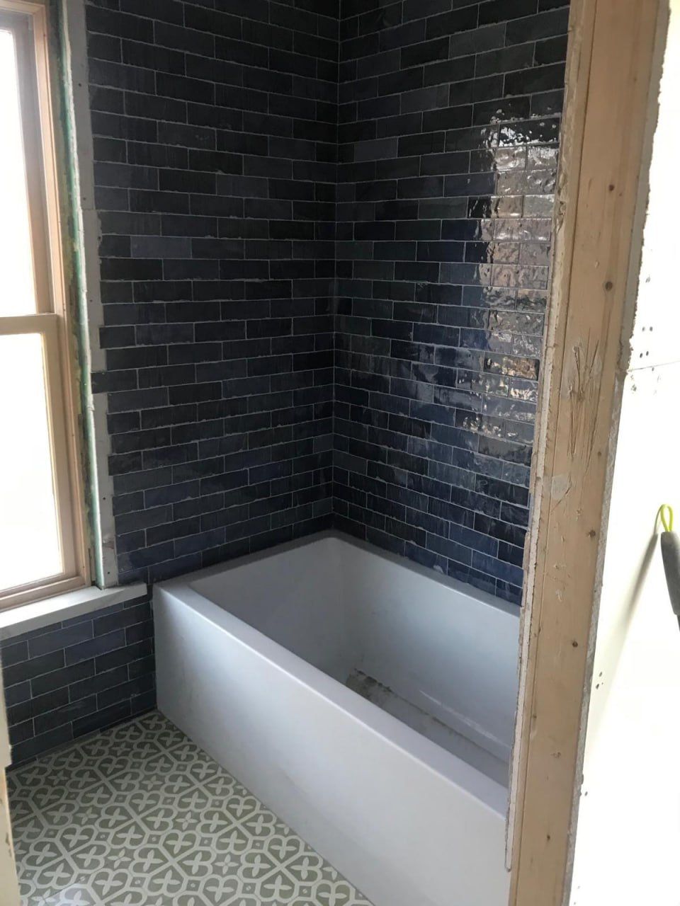 Navy subway tub surround with patterned floor in progress