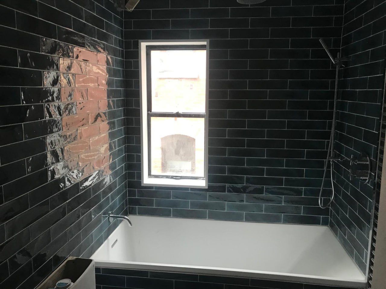 Deep teal subway tub surround with terracotta accent tiles