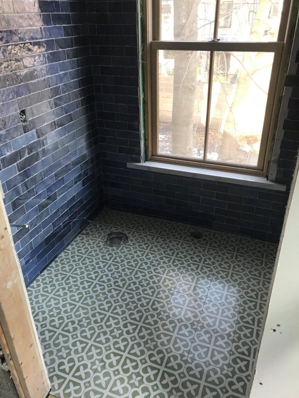 Deep blue subway walls with green encaustic floor