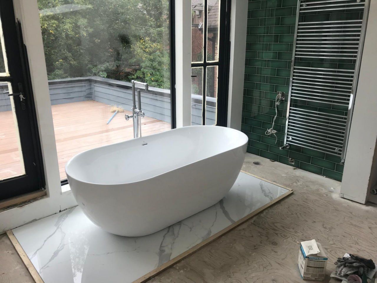 Freestanding tub with emerald tile and towel radiator