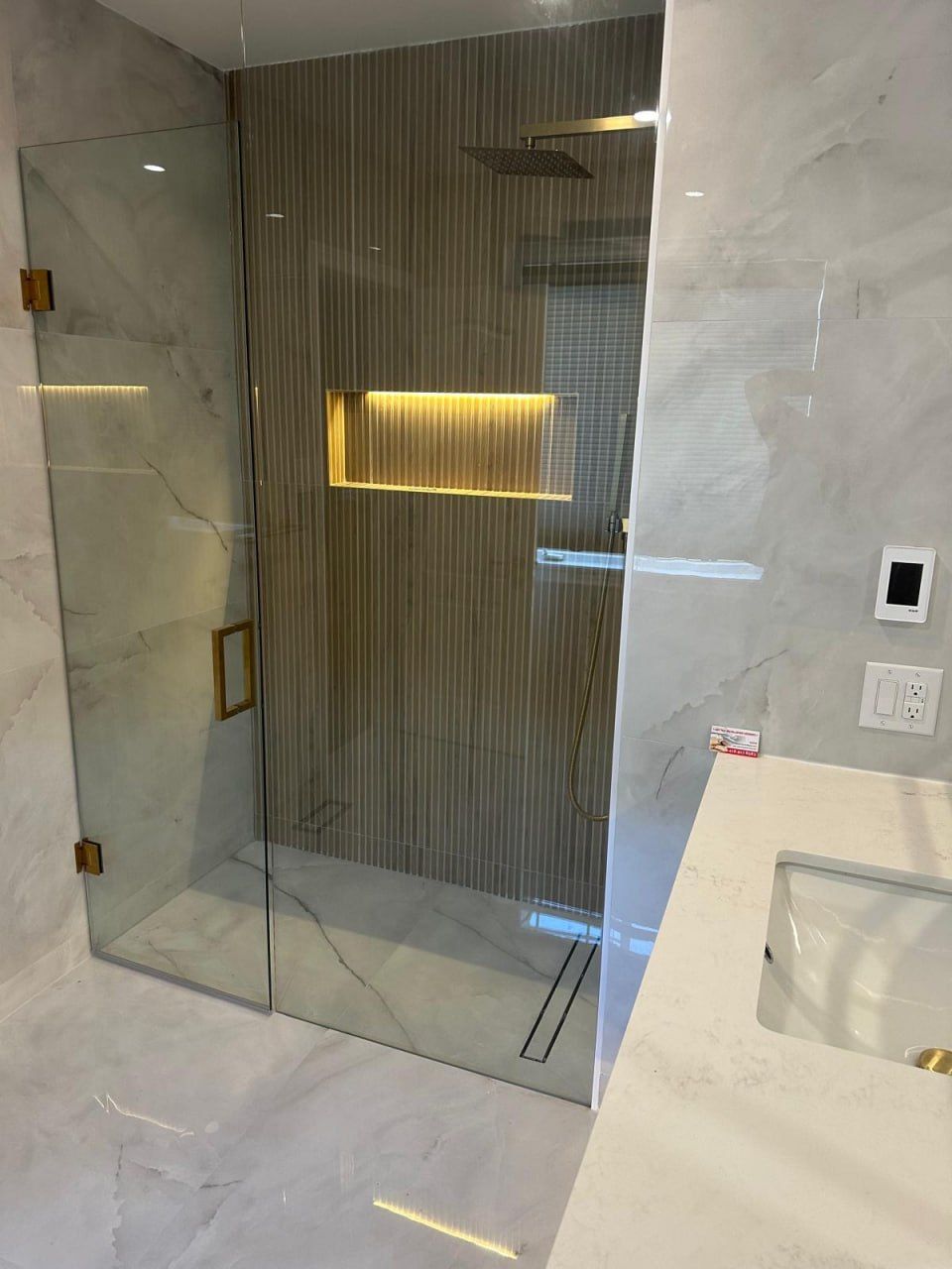 Fluted-tile shower with backlit niche and brushed gold fixtures