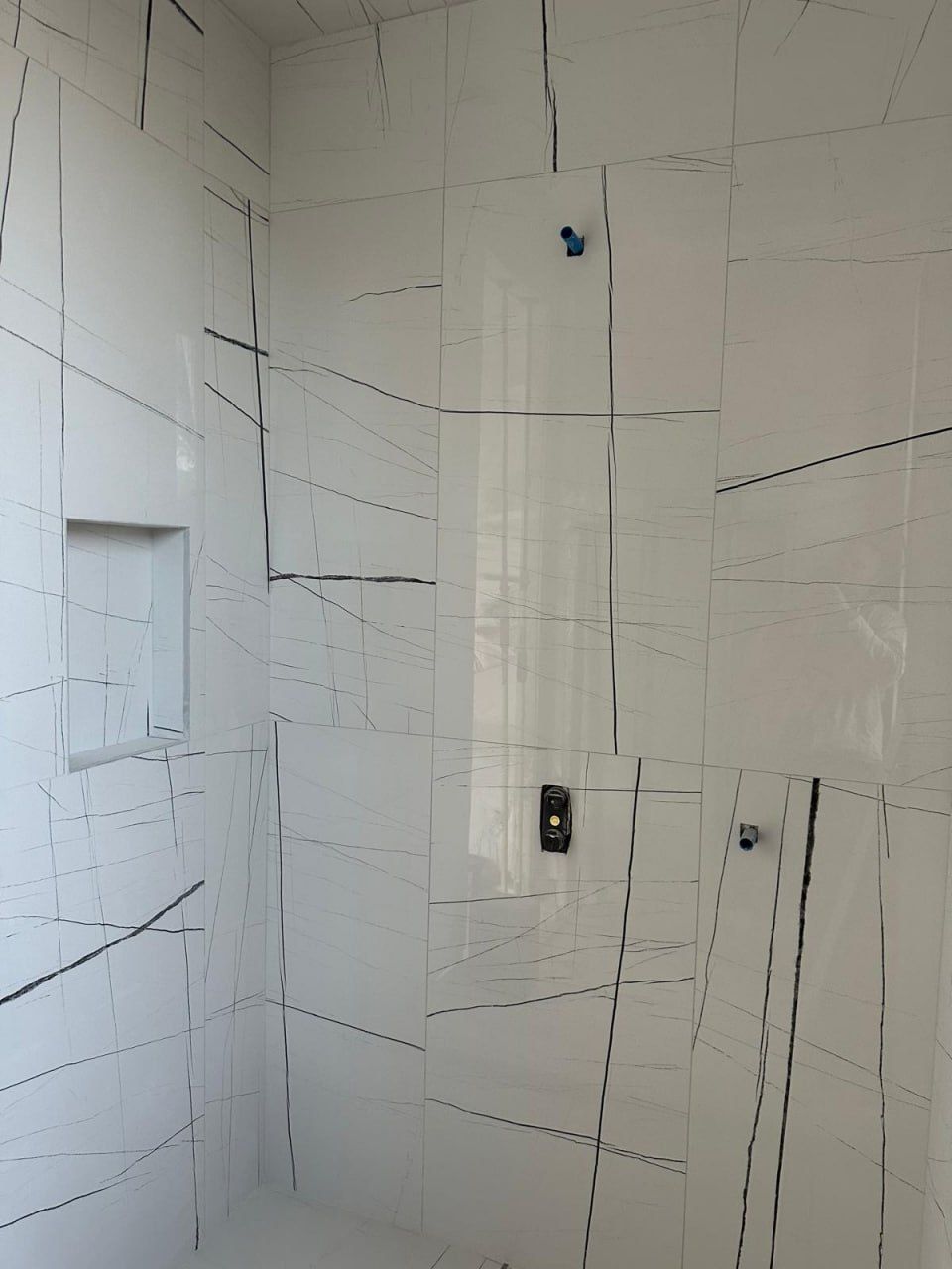 Veined marble-look large-format shower with recessed niche