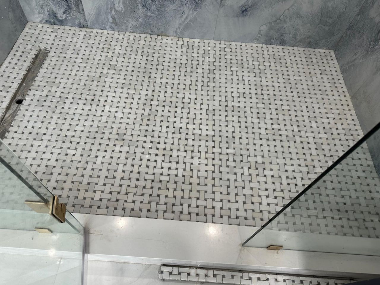 Basketweave marble mosaic shower floor with blue-grey marble walls